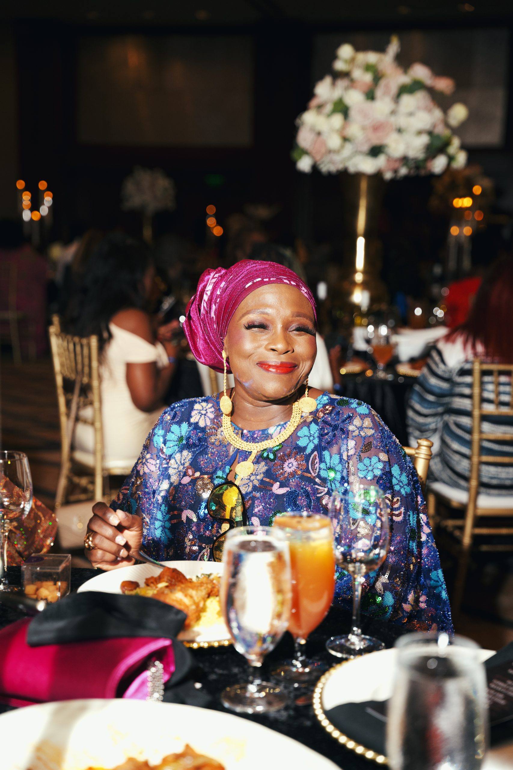African woman in traditional attire with headwrap and sunglasses